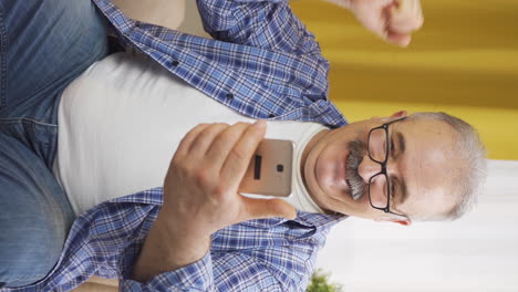 Vertical-video-of-The-old-man-looking-at-the-phone-is-happy.